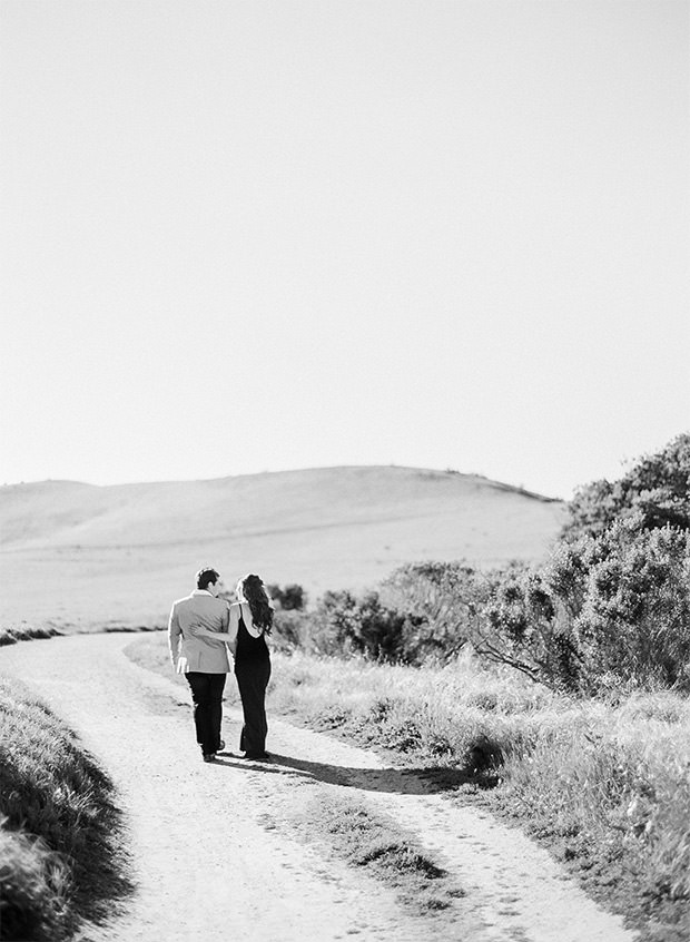 Black and white photograph of a couple walking together down a dirt road in Monterey, CA
