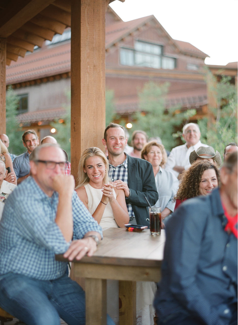 Guests smile during toast a the rehearsal dinner at High West Distillery