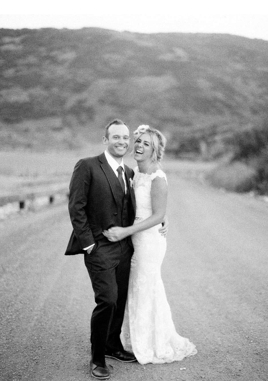 A happy bride and groom give a bountiful smile together in a gravel road in the mountains in Park City Utah. 