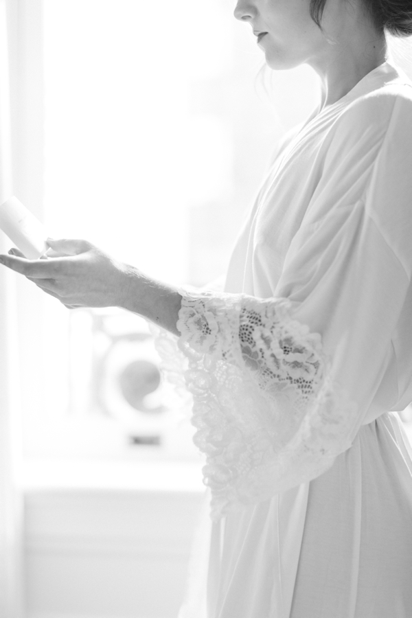Bride in a white lace robe reading her vows at the Palace Hotel in San Francisco. 