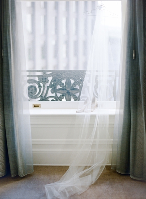 Champagne colored wedding heels are covered by a cathedral veil in a window of the Palace Hotel in San Francisco. 
