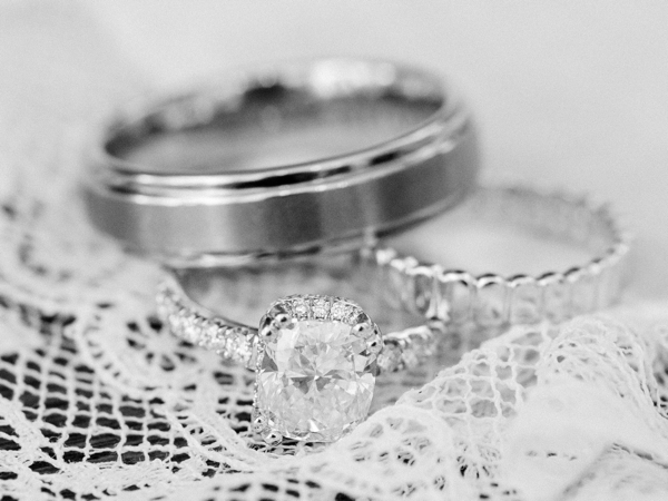 A black and white of wedding rings viewed closeup on lace. 