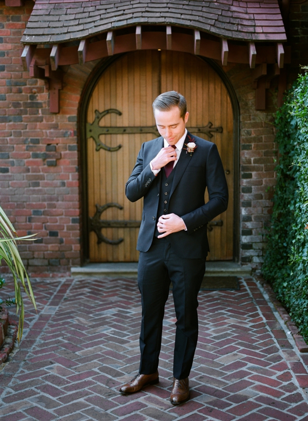 A groom adjusts his tie in front of the church doors of the Swedenborgian in San Francisco. 
