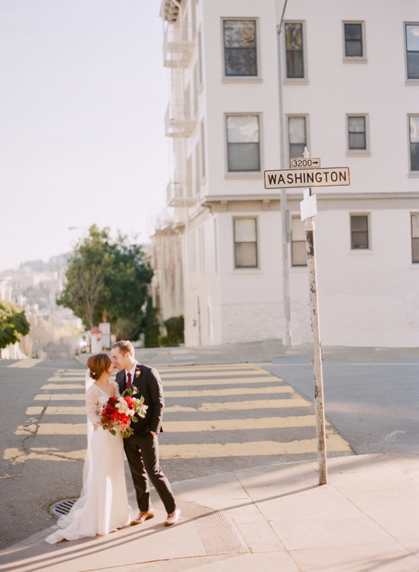 A bride and groom share a kiss on Washington Street in San Francisco.