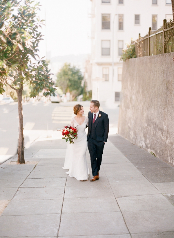 A bride and groom stroll down a city street in San Francisco.