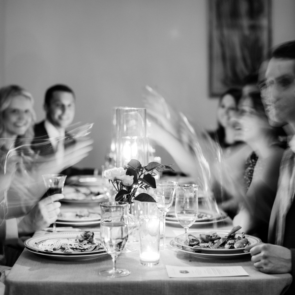Long exposure of wedding guests toasting together in black and white at an intimate wedding reception in San Francisco.