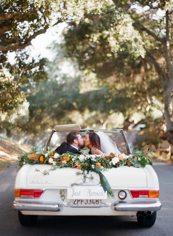 A bride and groom share a kiss in a floral decorated Mercedes convertible at Holman Ranch, CA. 