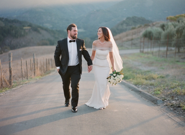 Bride and groom hold hands on a stroll through the beautiful Carmel Valley at Holman Ranch.