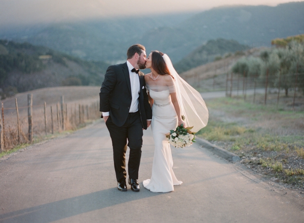 Bride and groom kiss on a stroll through the beautiful Carmel Valley at Holman Ranch