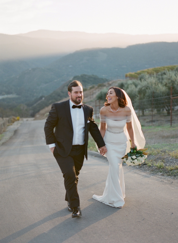 Bride and groom hold hands on a stroll through the beautiful Carmel Valley at Holman Ranch.