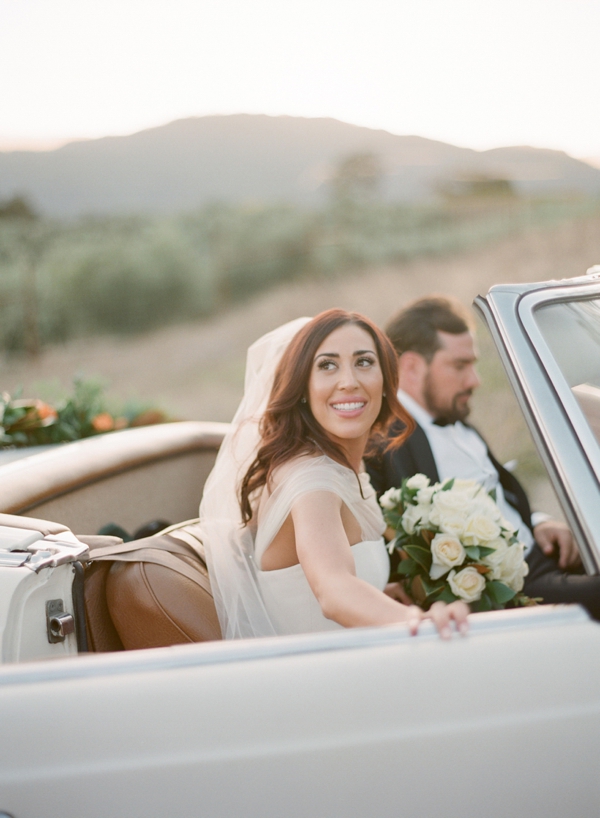 Beautiful bride steps in the the convertible getaway car at Holman Ranch.