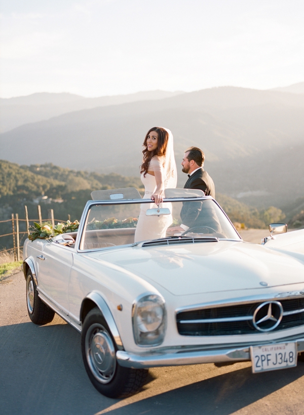 A bride stands in her white convertible Mercedes with her groom standing nearby at Holman Ranch in Carmel Valley