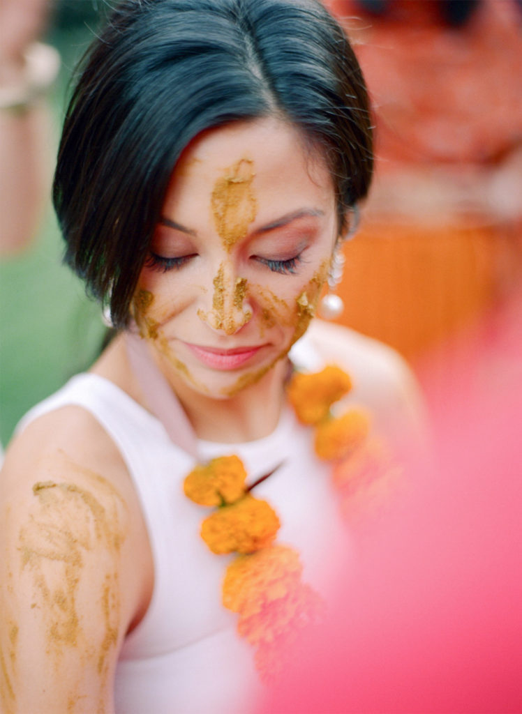 Jenna Lam sits surrounded by friends with golden turmeric paste on her face. 