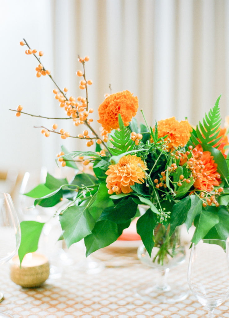 A honey orange flower arrangement sits decorating a dinner table.