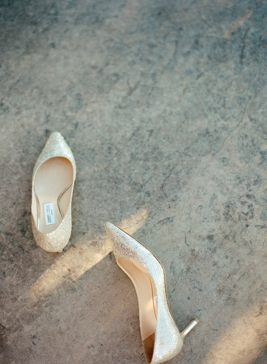 A guests's shoes, Manolo Blahniks, lay on the concrete with a slide of sunlight across them.