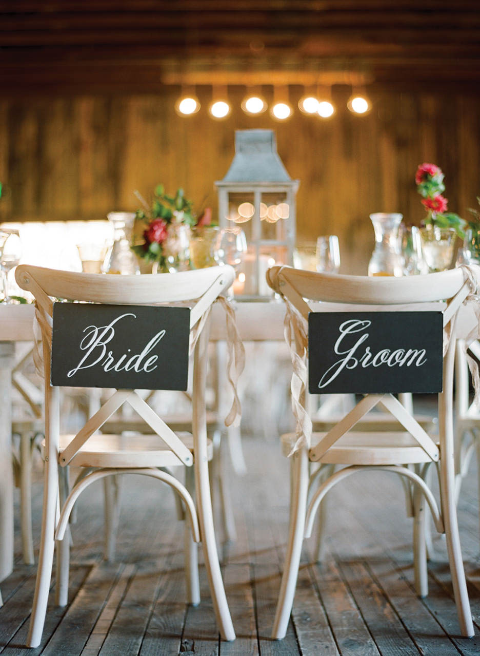 Bride and Groom signage is placed on the back of two dining room chairs for a chic wedding reception.