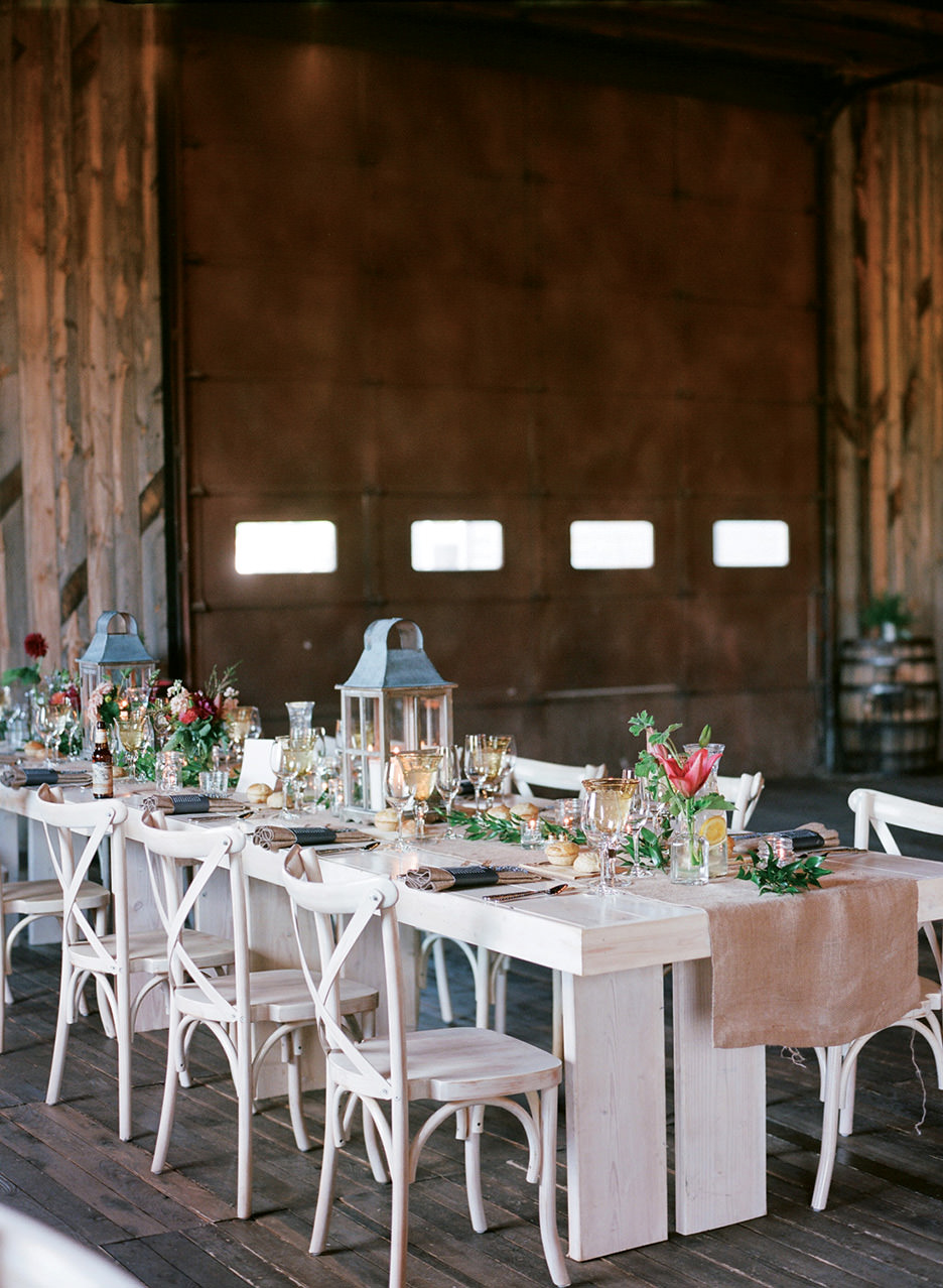Farmhouse and family style long tables line a sophicated barn reception.
