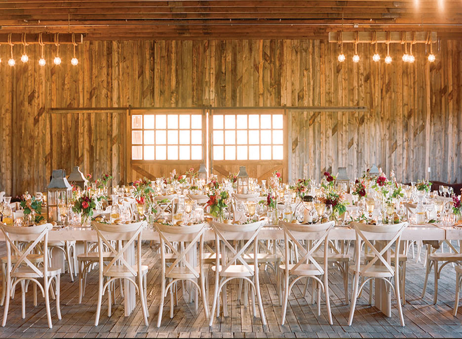 Farmhouse and family style long tables line a sophicated barn reception.