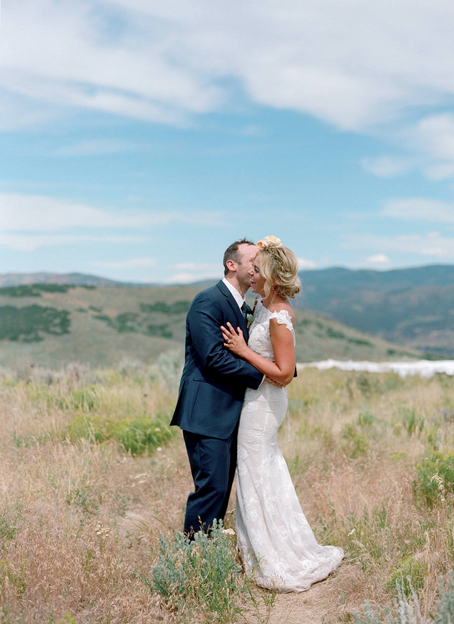 A bride and groom laugh together in a sweeping vista of Blue Sky Ranch in Utah.