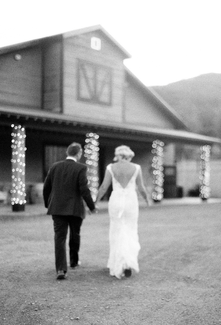 Black and white of bride and groom slightly blurry walking away into their ranch reception venue.