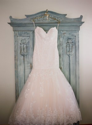 Wedding dress hanging on armoire with custom hanger