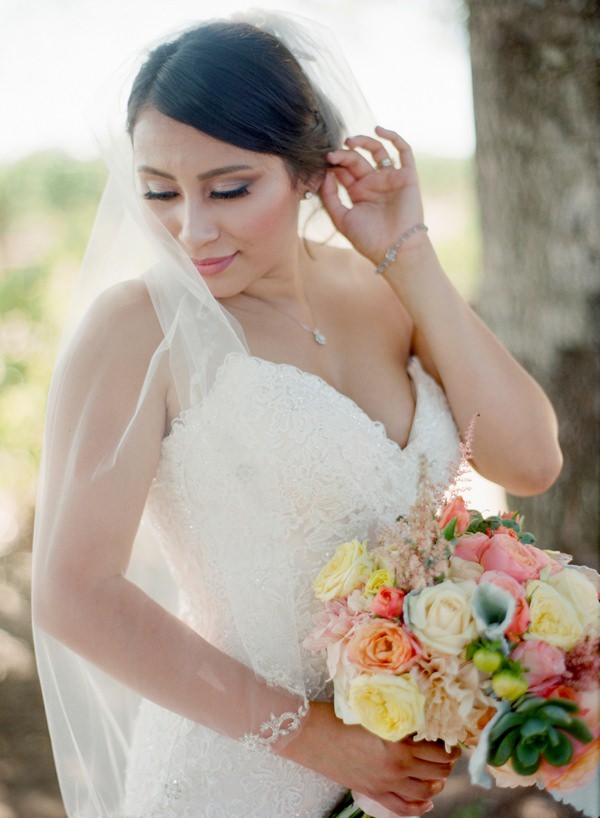 Bride holding bouquet and tucks hair behind her ear