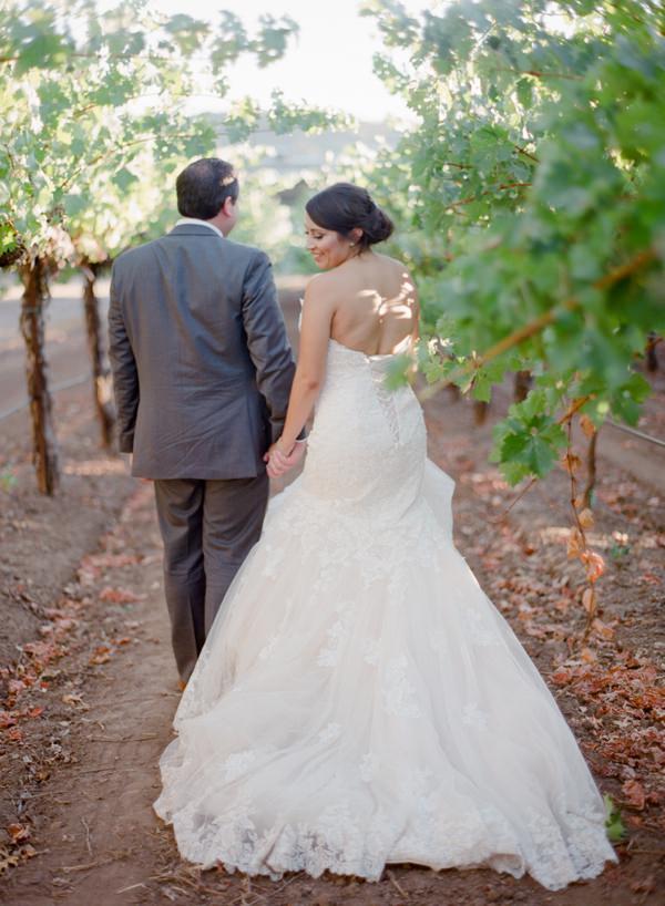 Bride and groom holding hands and walking in vineyards in Napa Valley