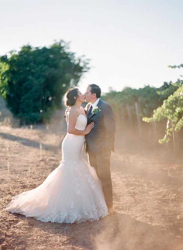 Bride and Groom kiss in a dusty path near vineyards in Napa Valley