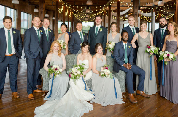 Wedding party pose by sitting and standing together in side the Biltwell event center