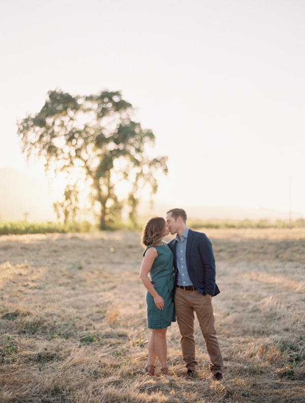 Couple exchanging a kiss in a sunlit field in Napa